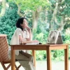 自然の中でテーブルに向かう女性のそばに置かれたコードレスソーラーファン