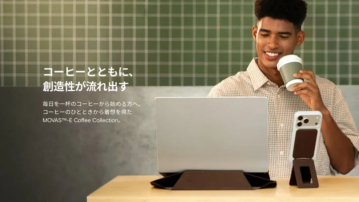 コーヒーを飲みながらノートPCとスマホスタンドを使用する男性