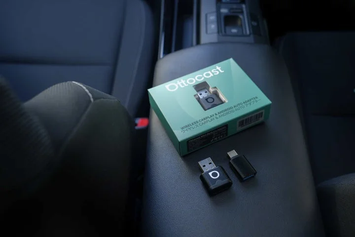 車内のセンターコンソールに置かれた製品パッケージと本体、USBアダプター