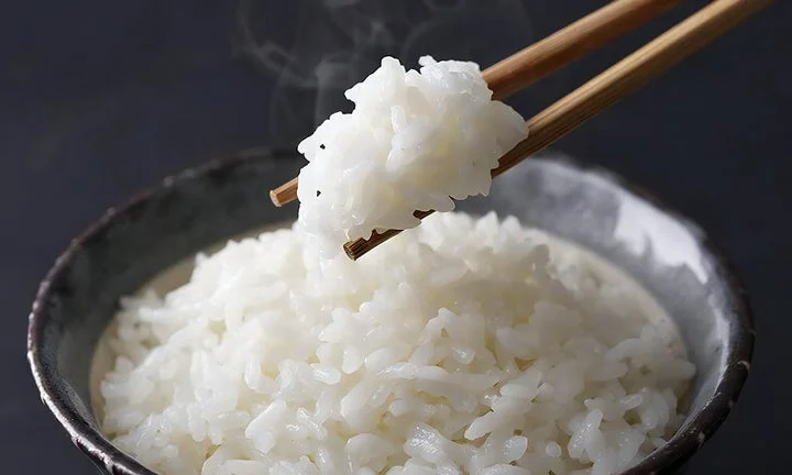 箸で持ち上げられた炊きたての白いごはん