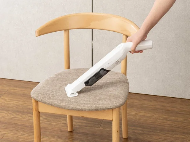 椅子の上に置かれたクッションをハンディクリーナーで掃除している様子
