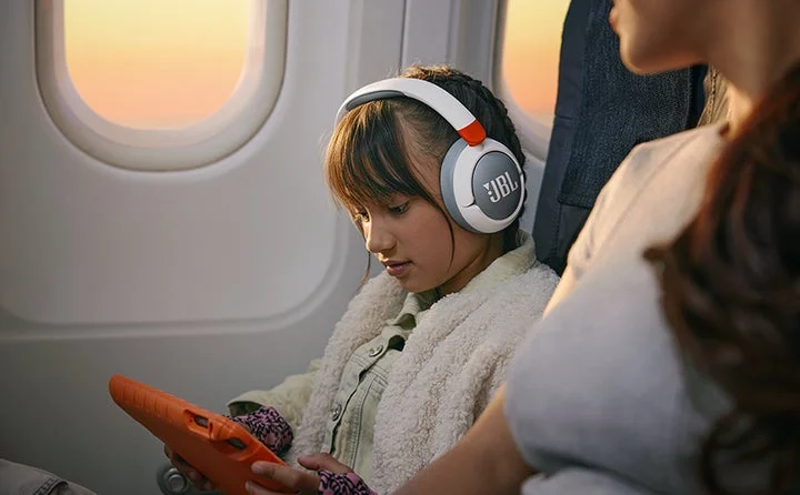 飛行機内でJBL Junior 470NCを装着してタブレットを見る子ども