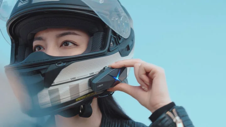 ヘルメットに装着されたインカムを操作するライダー