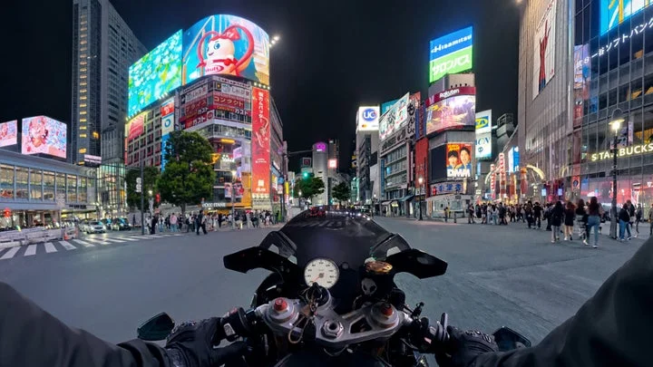 バイクのハンドル越しに見る夜の渋谷交差点