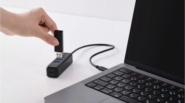 手でUSBハブにUSBメモリを差し込んでいる様子
