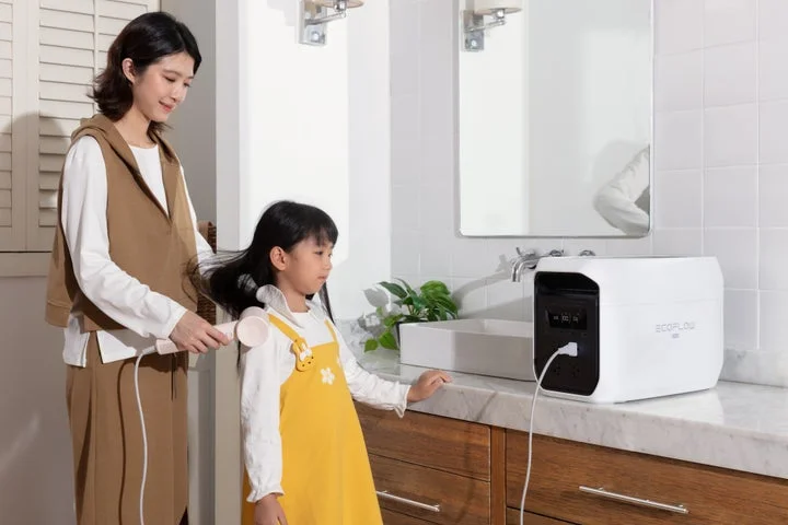 洗面所でポータブル電源から電源を取りドライヤーを使う様子
