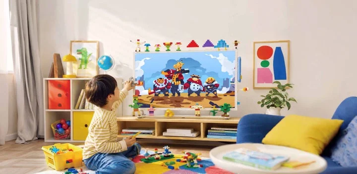 ブロックをテレビのフレームに取り付けて遊ぶ子どもの様子