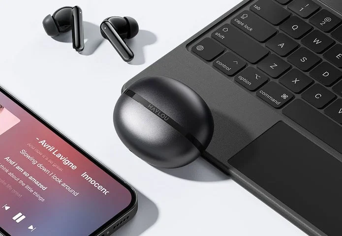 スマートフォンとPCの横に置かれた充電ケースとイヤホン本体