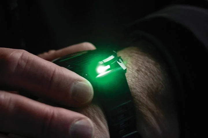 手首に装着した時計のLEDフラッシュライトが緑色に発光している様子
