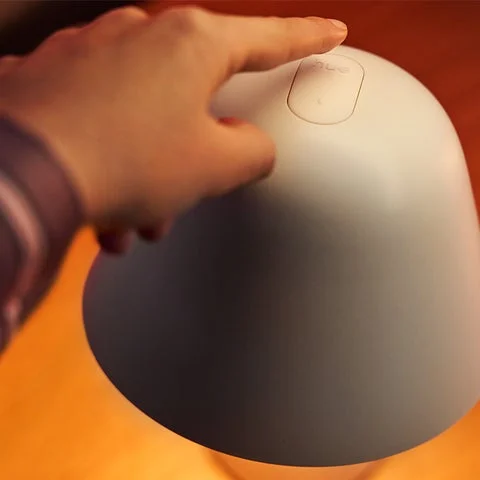 Philips Hueトワイライトベッドサイドライト上部の操作ボタンを指で押す様子