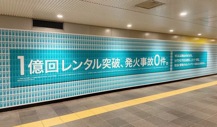 渋谷駅に掲出された「1億回レンタル突破、発火事故0件」を訴求する屋外広告