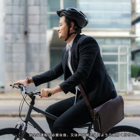 スーツ姿で自転車に乗る男性がイヤホンを装着している様子