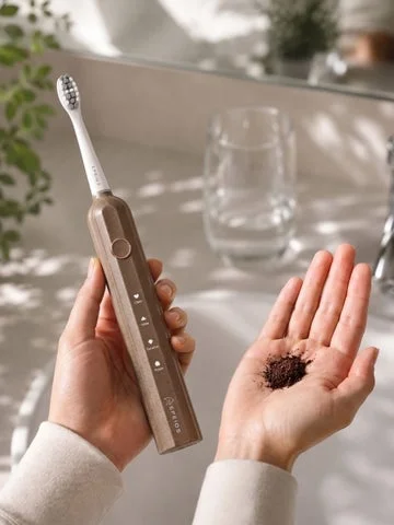 手に持ったEPEIOS電動歯ブラシと、手のひらに乗せられたコーヒーかす