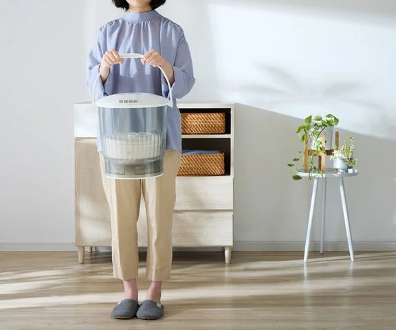 バケツ型洗濯機を持ち運ぶ様子
