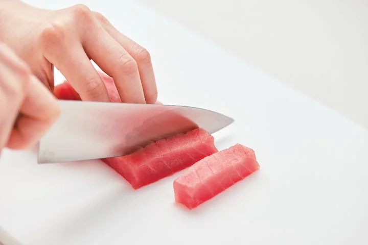 包丁で切り分けられている半解凍状態の刺身用マグロ