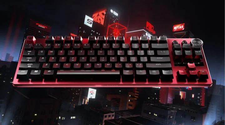 ネオンが輝く都市夜景を背景に、赤いアルミ製トッププレートのテンキーレスキーボードが配置されている