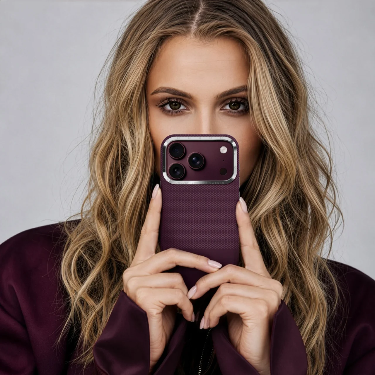 GC ESSENTIALSのバーガンディ色iPhoneケースを手に持った女性