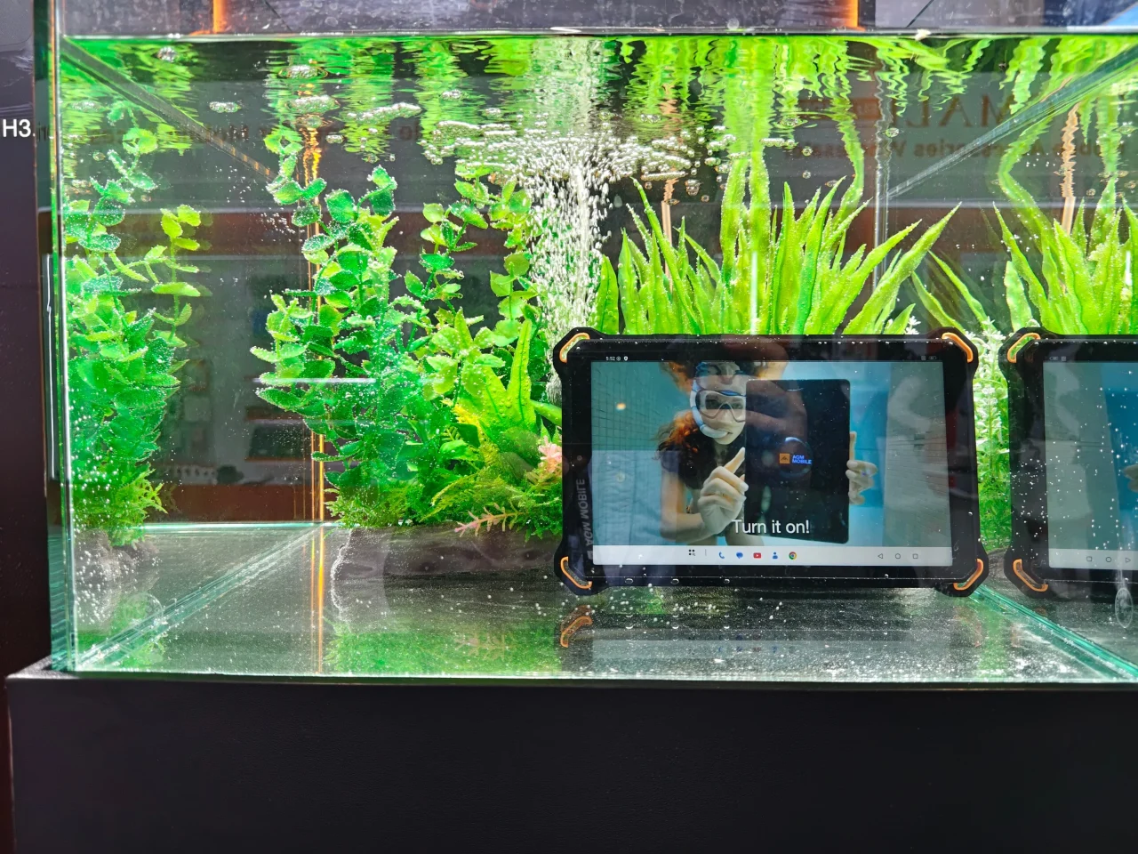 水槽に沈められたAGM PAD P3 Compactの防水性能を示す展示風景