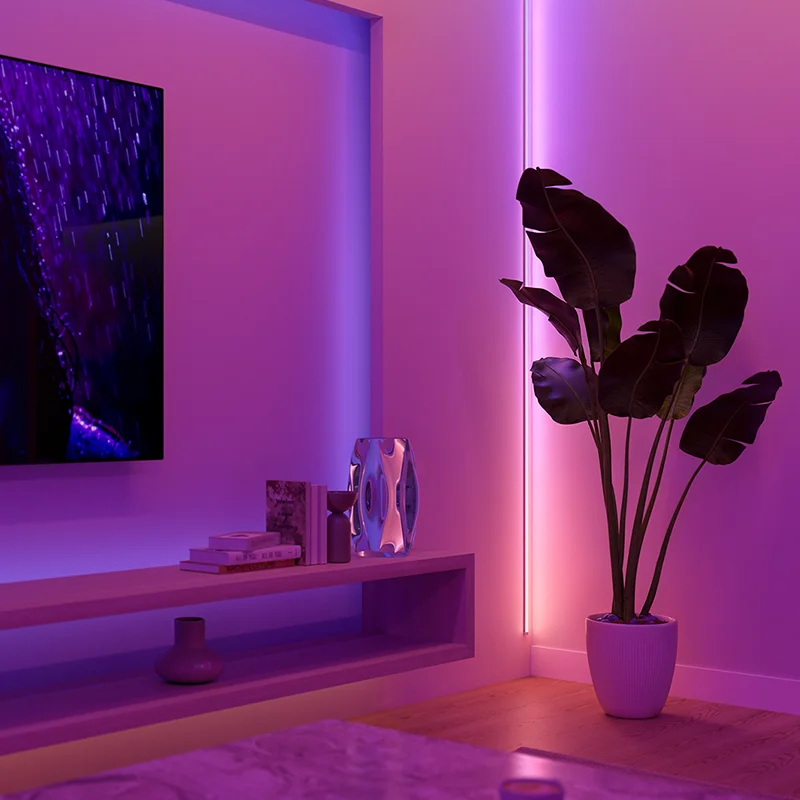 Hue オムニグロー テープライトが壁に設置され、紫とピンクの光で部屋を照らしている様子
