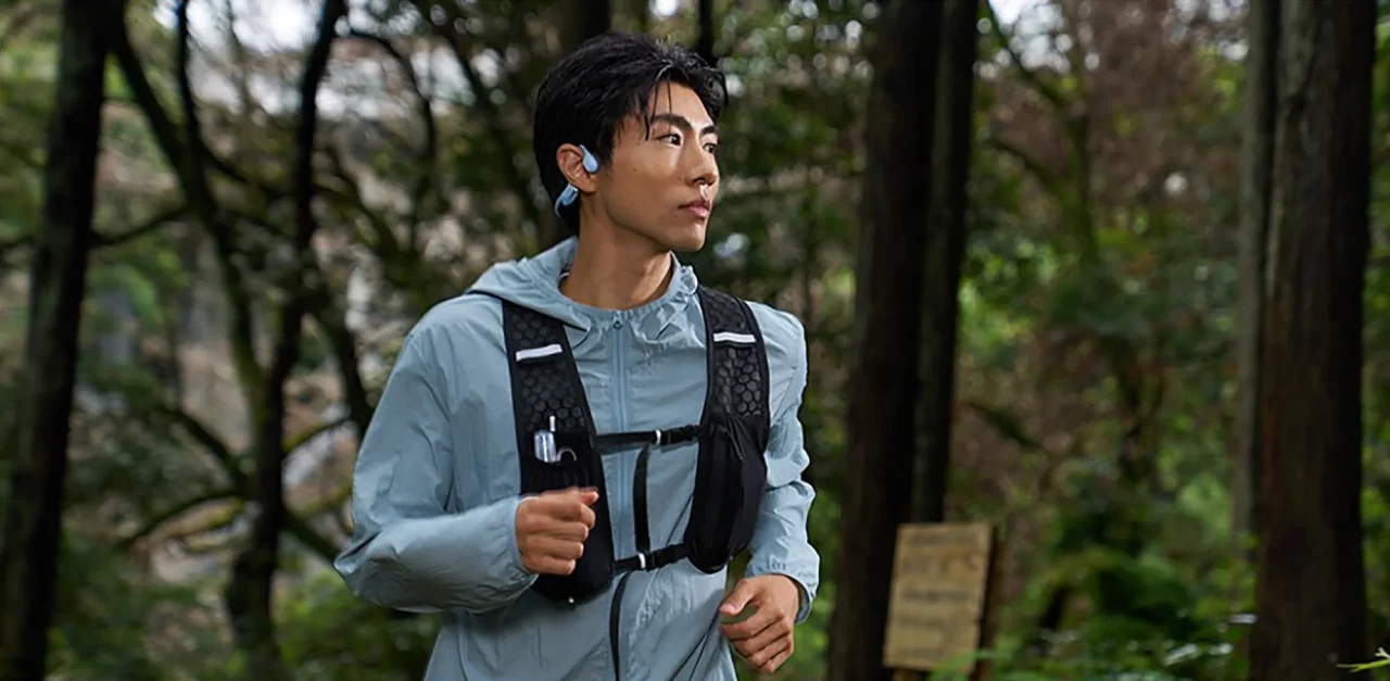 OpenRun Air 2を装着した男性が森の中でランニングする様子