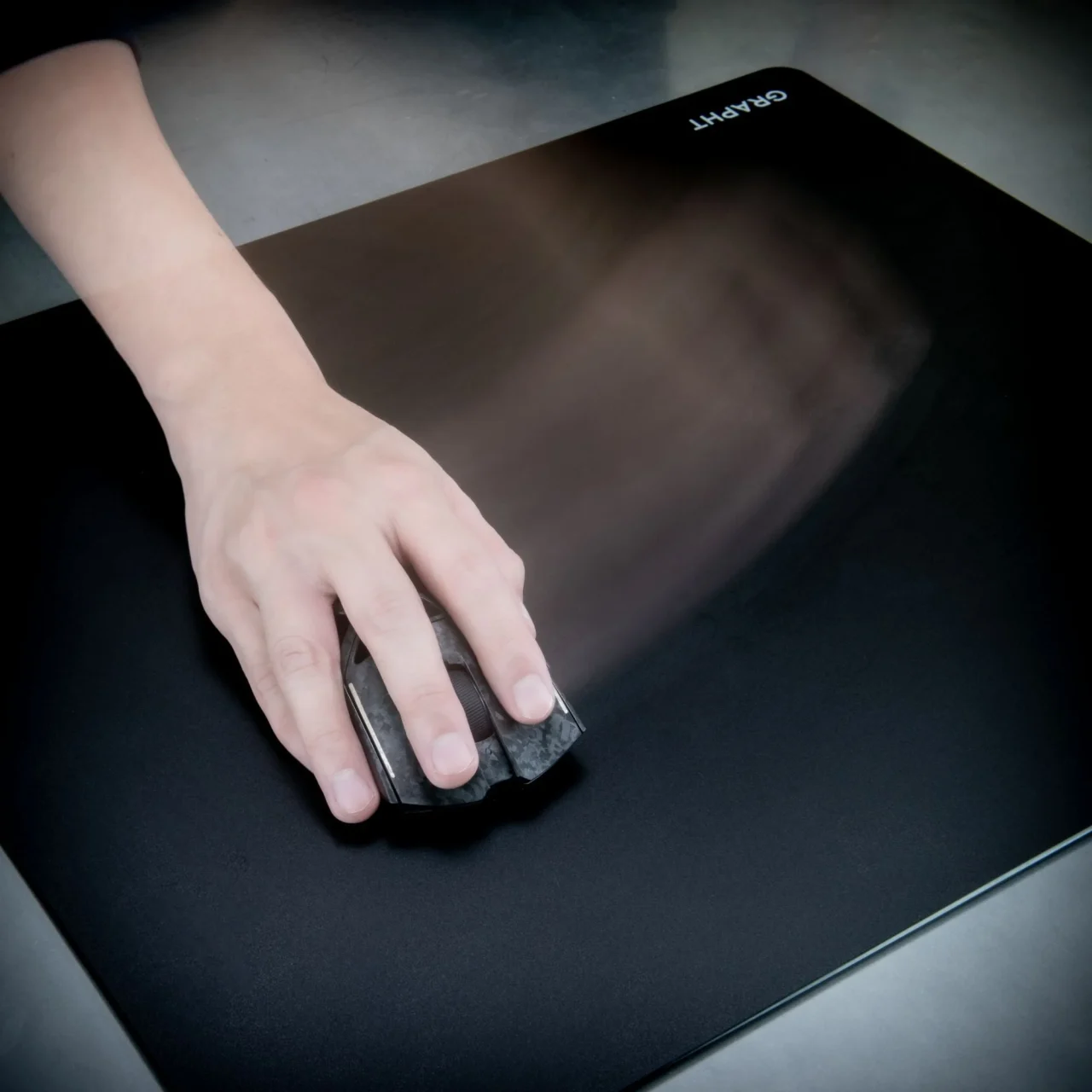 THE SHOOTER - Glass Mouse Pad Nexusの黒いガラス表面でマウスを操作する手元