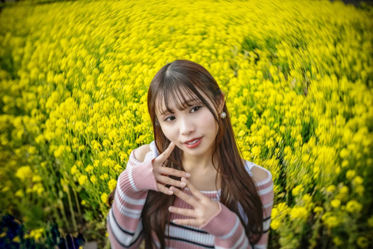 黄色い花畑を背景に、渦巻きボケで撮影された女性のポートレート