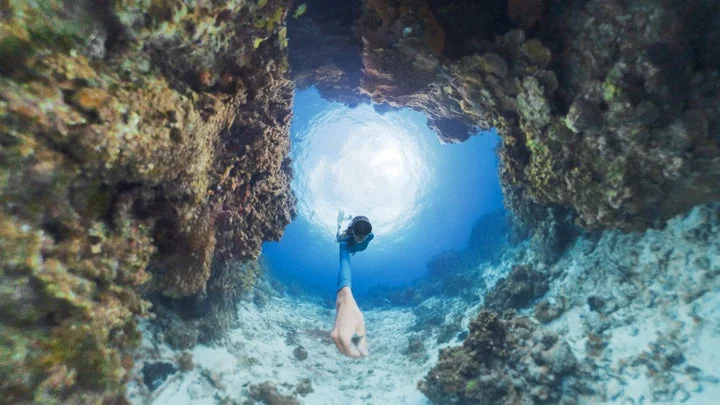 水中の洞窟から水面を見上げるダイバーの360度パノラマ映像