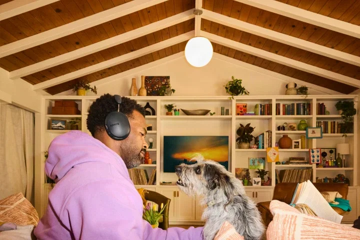 黒いSonos Ace Ultraを装着し、室内で犬と過ごす男性