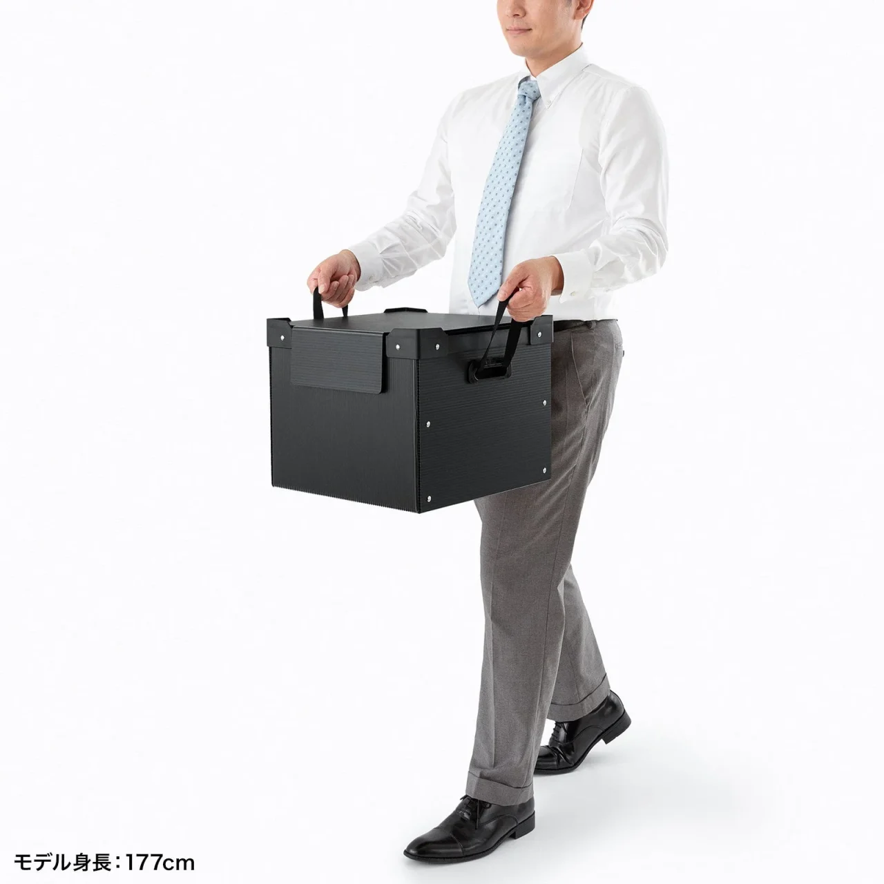男性が黒いプラダン製収納ケースを持ち運ぶ様子
