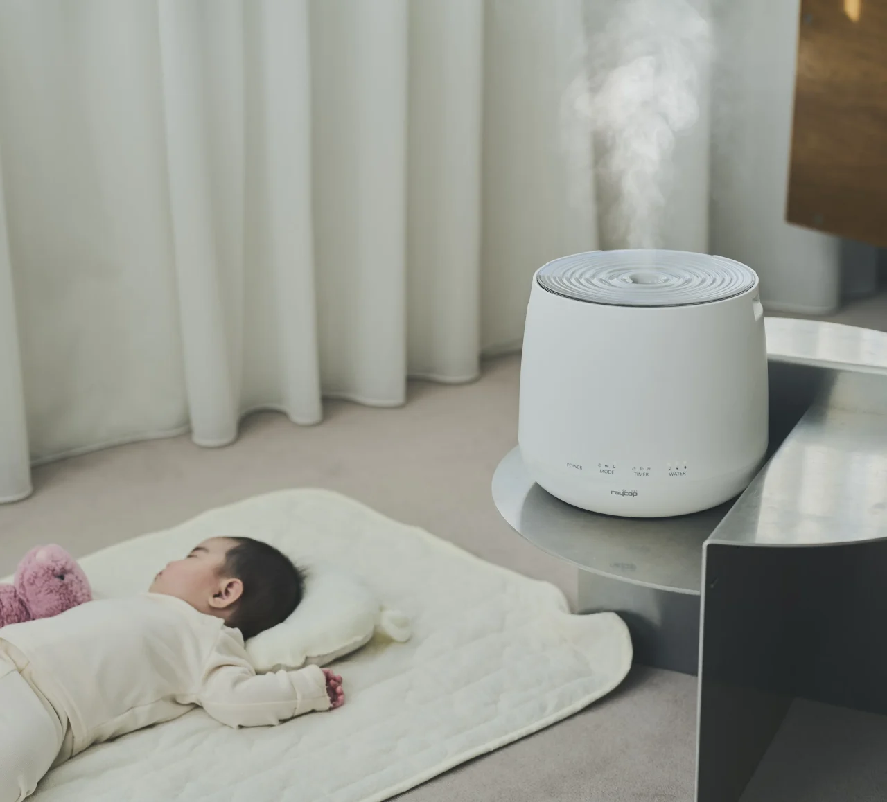 MINAMOの稼働シーン。ミストを放出する加湿器と、マットで寝る赤ちゃん。