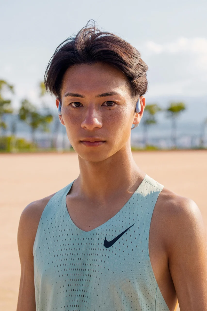 Shokzアスリート赤﨑暁選手がイヤホンを装着し、屋外で正面を向くポートレート