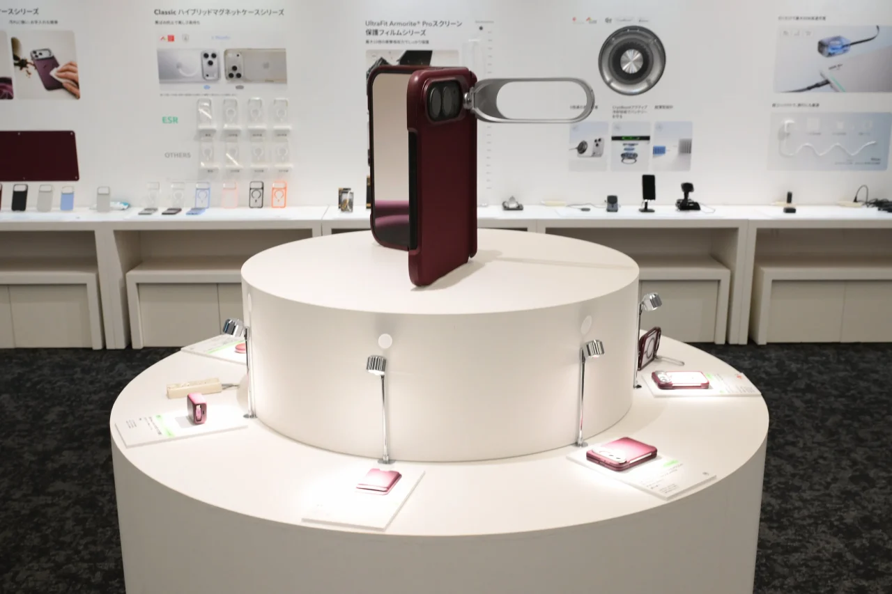 iPhone Duoをテーマにした展示スペースで、赤いケースの折りたたみスマホが円形台に展示されている