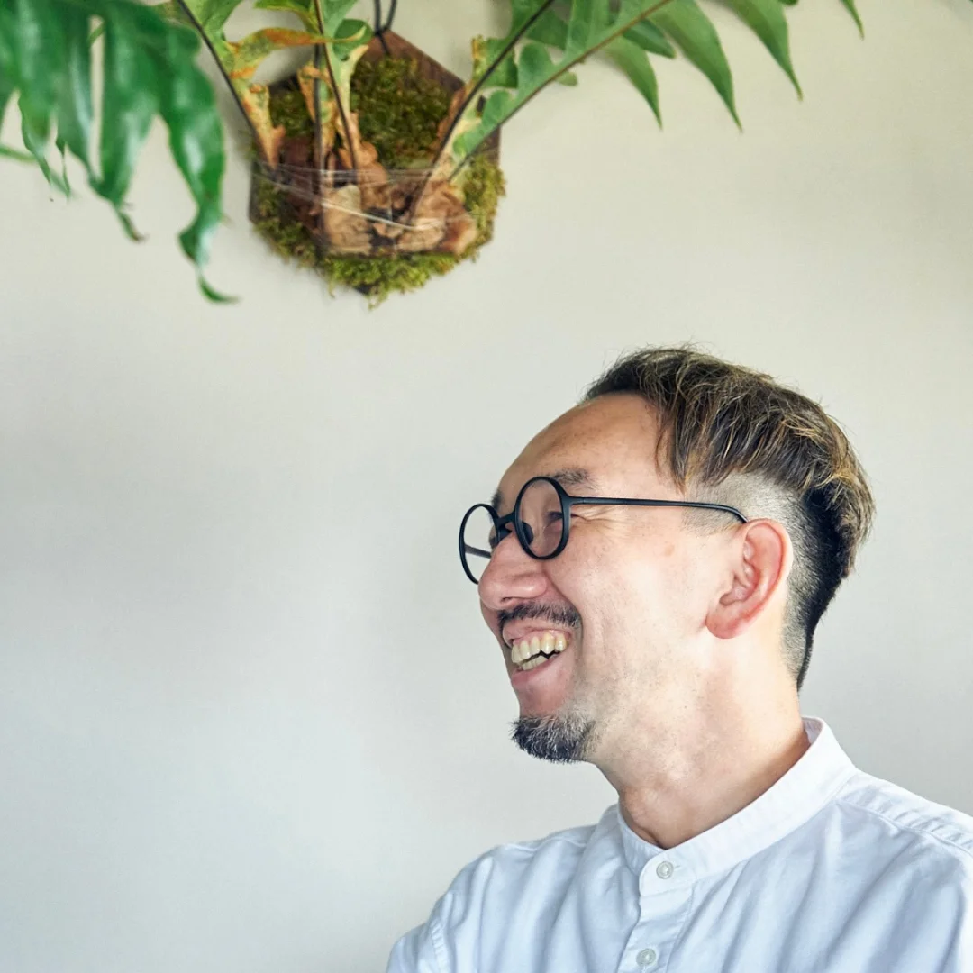 観葉植物のある空間で笑顔を見せる男性のポートレート