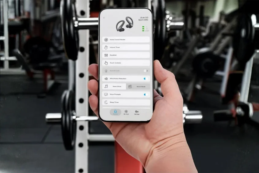 JLabアプリの画面を表示するスマホを手にした手元。背景はジム。