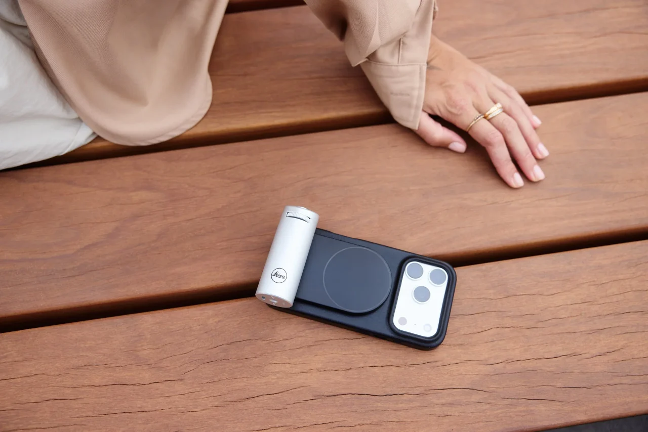 木製テーブルに置かれたiPhone 18 Pro用Leica LUXケースとシルバーグリップ