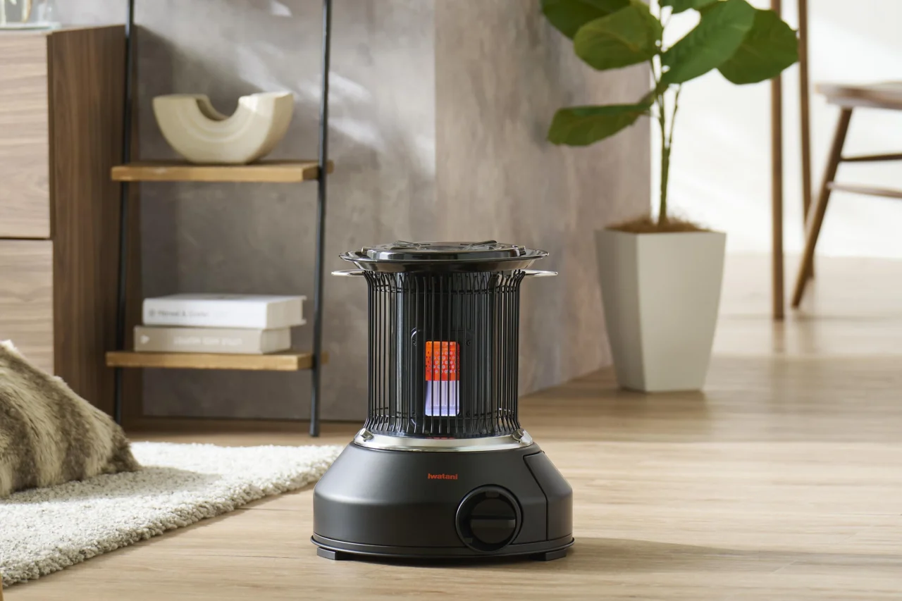カセットガスストーブ「マル暖プラス」の屋内使用イメージ。黒い本体が床に置かれている。