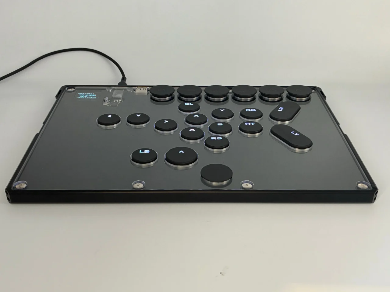レバーレスコントローラーRapidJAMの天板。黒いボタンとOLEDディスプレイが配置されたフラットな筐体。