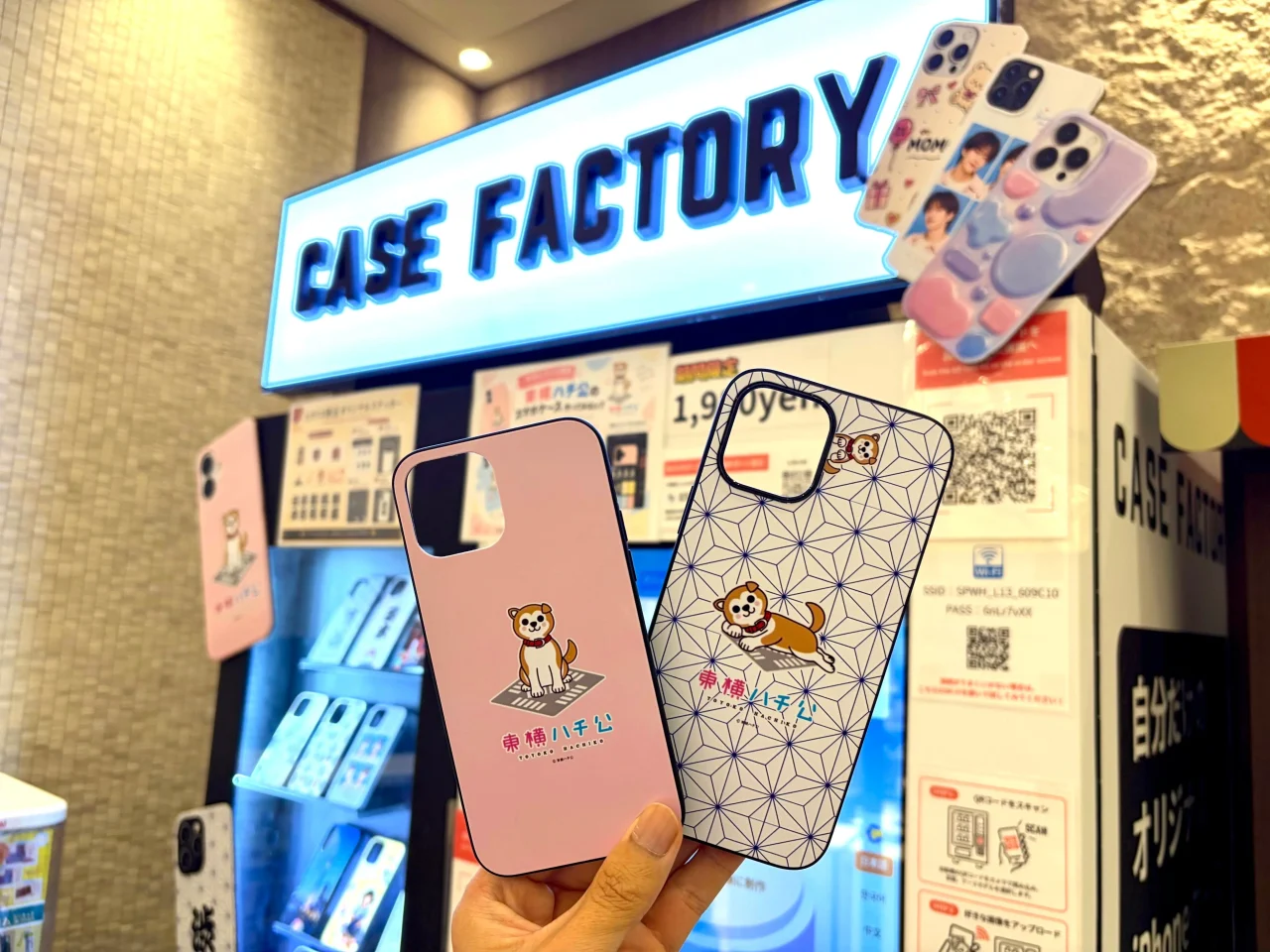 CASE FACTORY自販機前で東横ハチ公デザインのスマホケースを手に持った様子