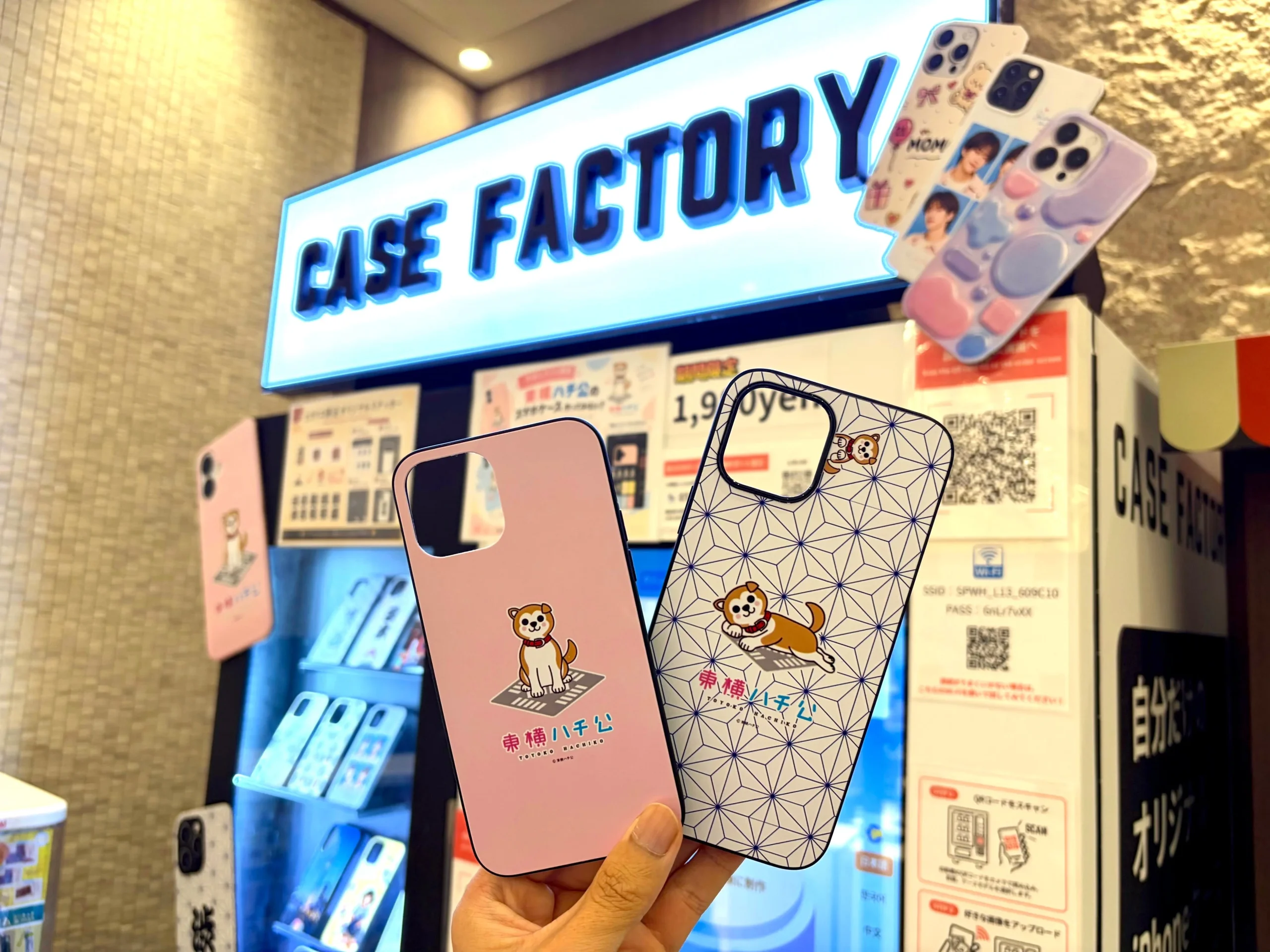 CASE FACTORY自販機前で東横ハチ公デザインのスマホケースを手に持った様子