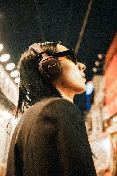 茶色のMilton A.N.C.を着け、街中で上を向く人物