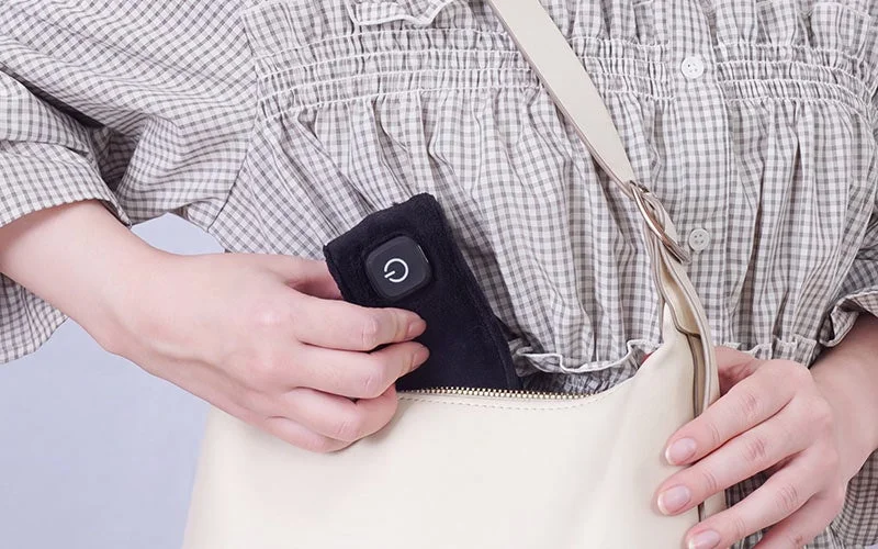 巻くだけUSBネックヒーター「ホッとネック」のスイッチ部をバッグに収納する様子