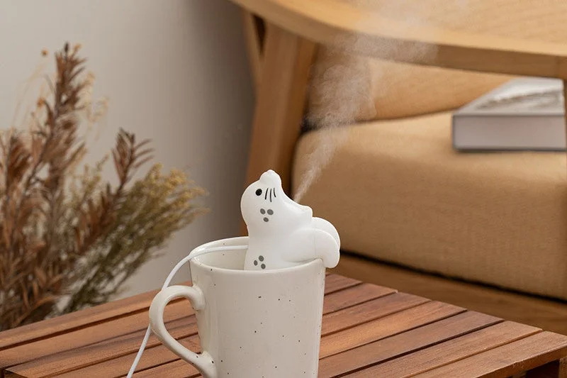 給電式ハングアニマルミストのゴマフアザラシがコップのふちに掛かり、口からミストを噴霧している様子