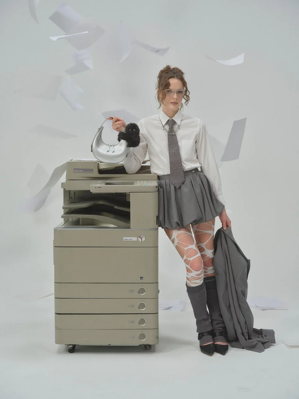 コピー機に寄りかかるモデルが、手に持った白いバッグにmirumi BLACKを装着している姿