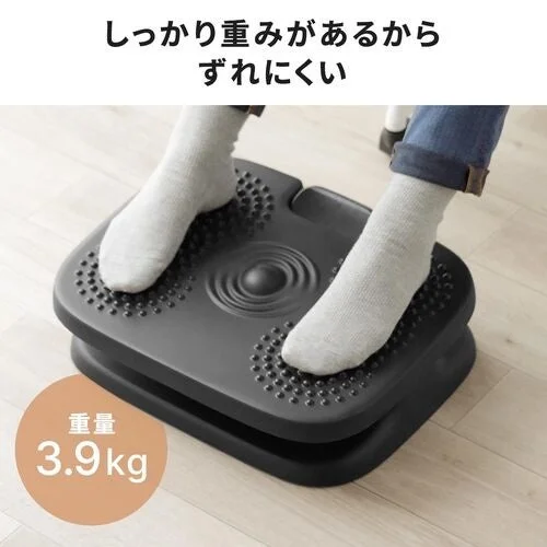 白い靴下を履いた両足を乗せた、黒い凹凸付きフットレスト