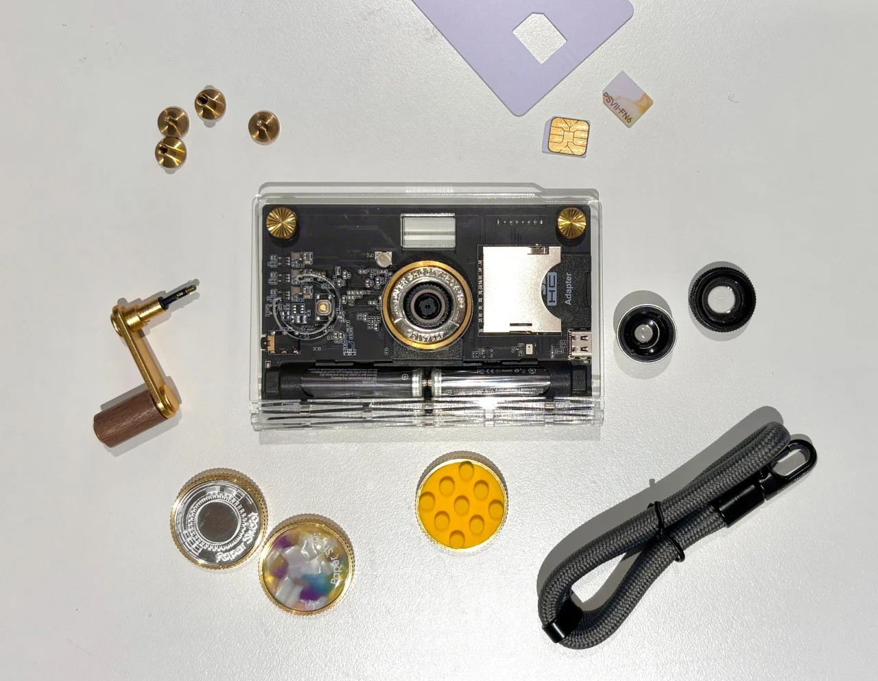 PaperShootの透明ケースのカメラと周囲に並べた付属品