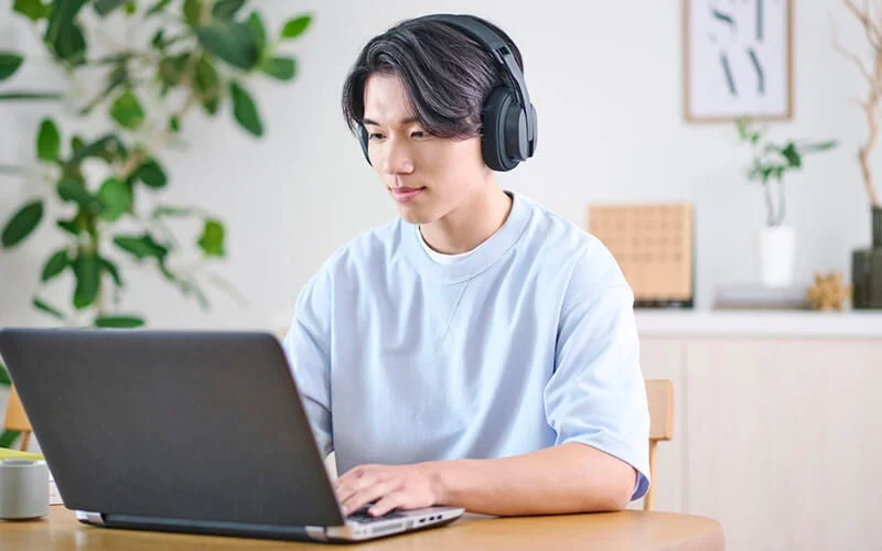 フレキシブルアームのマイクを外した状態で、ノートPCを操作する男性の姿