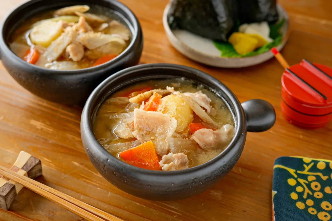 オートクックポットでつくる具だくさん豚汁。黒い器にじゃがいもやにんじん、豚肉が入った汁物が写る。