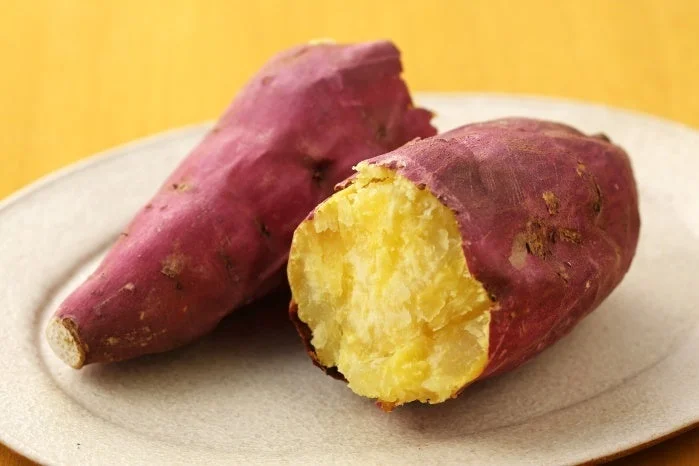 ガラスエアフライヤーでつくるほくほく焼き芋。紫の皮のさつまいもが2本、白い皿に盛られています。