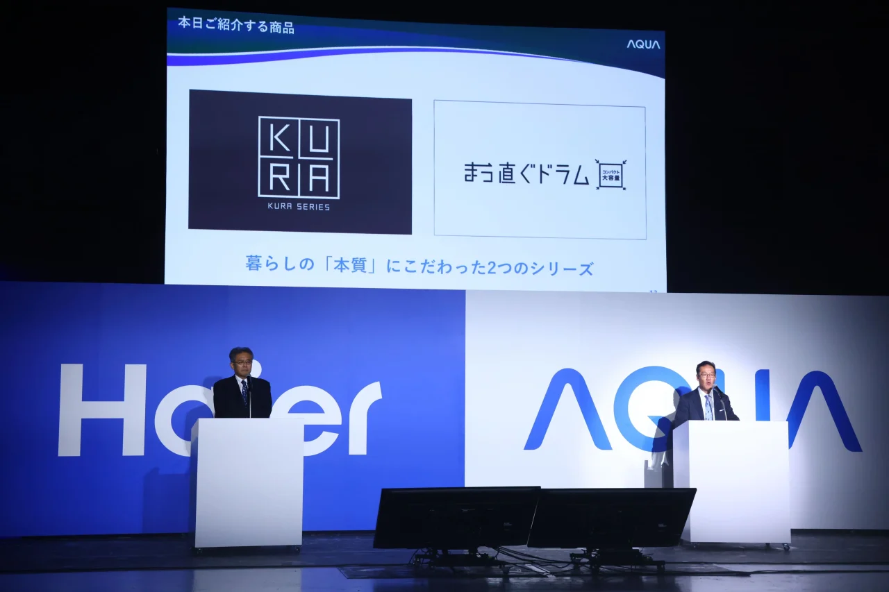 KURAとまっ直ぐドラムの紹介画面を背に、2人が演台に立つ企業パート