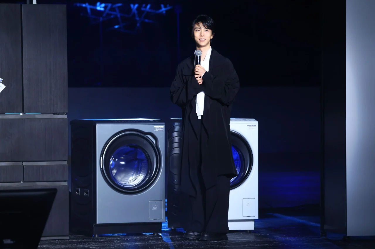 ドラム式洗濯機を背にマイクを持って話す羽生結弦さん